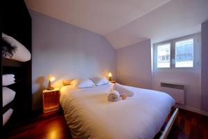a bedroom with a large white bed with two lights at Le toit des Carmes in Rouen