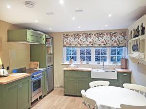 a kitchen with green cabinets and a table and a window at Freshwater Barn in Benenden