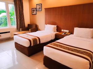 a hotel room with two beds and a chair at La Franklin Hotel in Bhubaneshwar