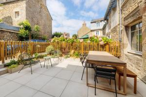 a patio with a wooden table and chairs at Belle maison 8 personnes à 600m de la plage avec parking privé in Dinard