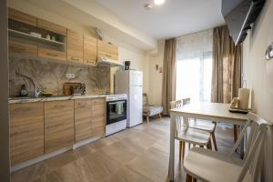 a kitchen with wooden cabinets and a table with chairs at Dimitra Beach Apartments 2 in Nea Karvali
