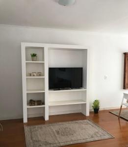 a white entertainment center with a television in a living room at Plaza Mitre, departamento 2 dormitorios in San Nicolás de los Arroyos