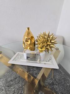 a table with a gold vase and plants on it at Apartman Central Lux in Banja Luka