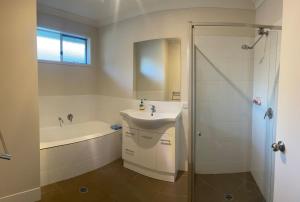 a bathroom with a sink and a tub and a shower at Accomodation at Lavington in Lavington +29 photos