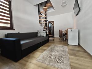 a living room with a black couch and a spiral staircase at ADAM-OASIS in Borzont
