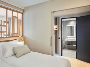 a bedroom with a white bed and a bathroom at Aparthotel Adagio Stuttgart NeckarPark in Stuttgart +54 photos
