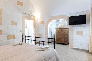 a bedroom with a bed and a tv on a wall at Casa Roma 78 Traditional Stone House in Monopoli Center in Monopoli