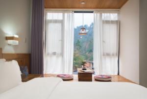 a bedroom with a bed and a large window at Astria Moruo Retreat in Xinglong