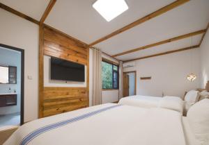 a bedroom with two beds and a flat screen tv at Astria Moruo Retreat in Xinglong
