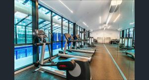 a gym with rows of tread machines and a pool at Banana Bliss - Spacious 2 Bedroom CBD Apartment with 2 Balconies, 2 Bathrooms & Parking Option in Melbourne