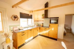 a large kitchen with wooden cabinets and a window at Sauke Jaap in Buren +7 photos