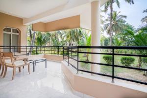 a balcony with a table and chairs and palm trees at Toshali Sands Puri in Puri