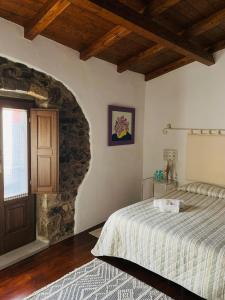 a bedroom with a bed and a stone wall at The Templars Guesthouse in Santu Lussurgiu