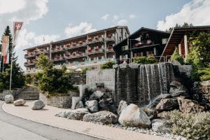 a hotel with a waterfall in front of a building at Parkhotel Schoenegg in Grindelwald
