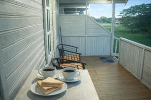 a table with two cups of coffee and sandwiches on a porch at Fideluna Beach Bungalow in Insyurifuri +9 photos