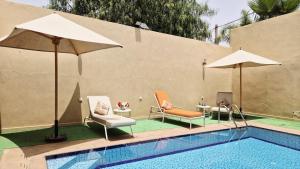 a swimming pool with two chairs and umbrellas next to at Modern Design Villa Private Pool Marrakech in Marrakesh