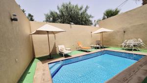 a swimming pool with chairs and tables and umbrellas at Modern Design Villa Private Pool Marrakech in Marrakesh