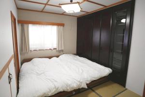 a bedroom with a white bed and a window at リトリート奥入瀬屋 in Towada