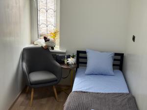 ein kleines Schlafzimmer mit einem Bett, einem Stuhl und einem Fenster in der Unterkunft Kust Hostel in Kiew