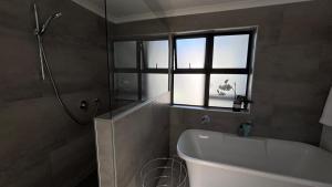 ein Badezimmer mit Badewanne, Waschbecken und Fenster in der Unterkunft Flip-Flops studio in Hermanus