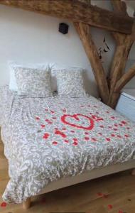 a bed with a white bedspread with red flowers on it at Le Loft in Suèvres