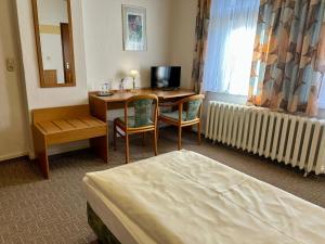 a hotel room with a desk and a bed at Benz Café & Pension in Blankenburg