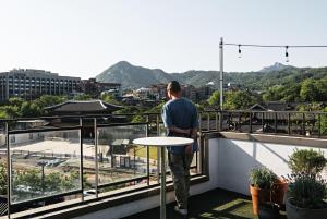 a man standing on a balcony looking out at the city at Unplug Anguk in Seoul