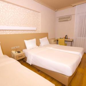 two beds in a room with two white beds at Esin Hotel in Denizli