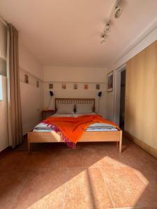 a bedroom with a bed with an orange blanket on it at Gästehaus Stefan Koch in Rust