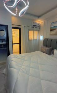 a bedroom with a large white bed and a chandelier at D2H résidence in Abidjan