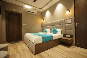 a bedroom with a large bed with blue pillows at Hotel Mantra Inn in Haridwār +116 photos