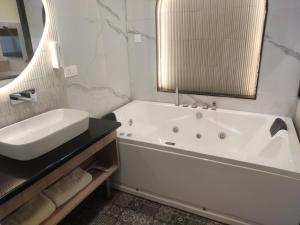 a white bathroom with a tub and a sink at Hotel Pallavi Grand in Panchkula +25 photos