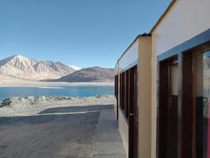 a building with a view of the water and mountains at Pangong Mentsel Cottage in Lukung