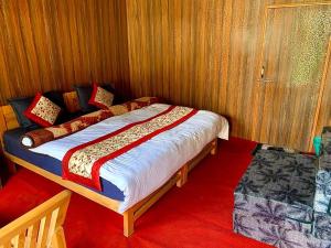 a bed in a room with wooden walls at Pangong Mentsel Cottage in Lukung