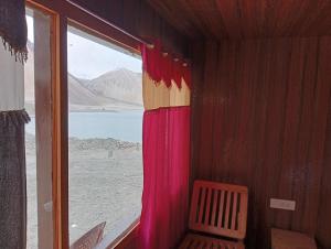 a room with a window with a view of the desert at Pangong Mentsel Cottage in Lukung +2 photos