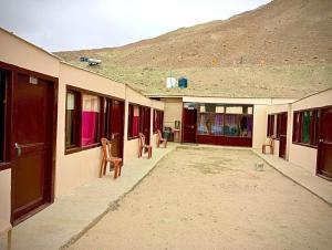 a building with chairs and a mountain in the background at Pangong Mentsel Cottage in Lukung