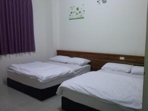 two beds in a room with white sheets at Lu He Feng Homestay in Luodong