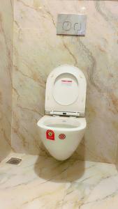 a white toilet in a bathroom with a marble wall at SOALTEE Near Lucknow Airport in Lucknow