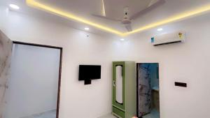 a white room with a toilet and a tv on the wall at SOALTEE Near Lucknow Airport in Lucknow