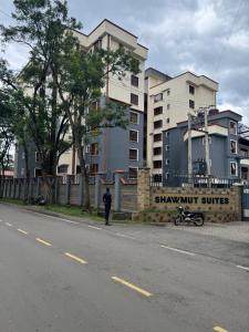 a man standing on the side of a street with a building at Raha Home within Nakuru CBD with pool and gym in Nakuru