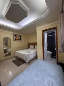 a bedroom with two beds and a bathroom at Hotel Flor do Pari in São Paulo