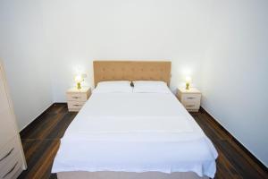 a bedroom with a white bed and two night stands at Sunny Breeze Hotel in Vlorë