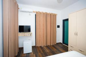 a bedroom with a bed and a tv and curtains at Sunny Breeze Hotel in Vlorë