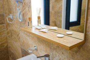 a bathroom with a wooden shelf with a sink and a mirror at Sunny Breeze Hotel in Vlorë +49 photos