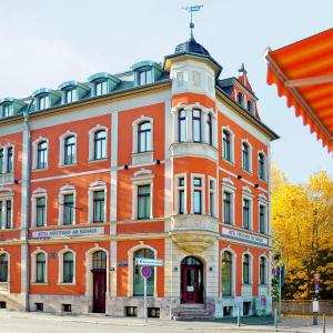 ein großes orangefarbenes Backsteingebäude mit einem Uhrturm in der Unterkunft Hotel & Apartments Fürstenhof am Bauhaus in Weimar
