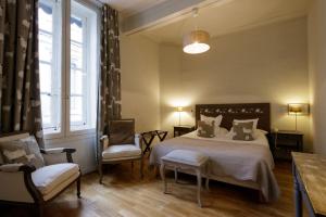 a bedroom with a large bed and two chairs at Hôtel l'Amphithéâtre in Nîmes