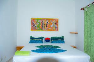 a bedroom with a white bed with a painting on the wall at Résidence KEUR FLEURIE in Rufisque