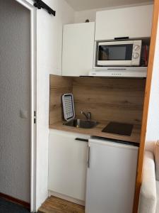a small kitchen with a microwave and a sink at Studio Tignes Val Claret in Tignes