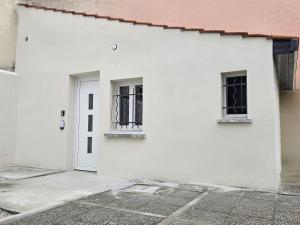 a white house with two windows and a door at Maisonnette Grande Hauteur Proche Paris & Stade De France in Drancy