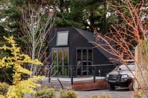 a black tiny house with a car parked in front at Romantic luxury tiny home in an idyllic setting in Glenquarry